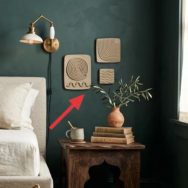 Four handcrafted textured wall art panels in natural beige, featuring abstract patterns like spirals and waves, mounted on the dark green wall.