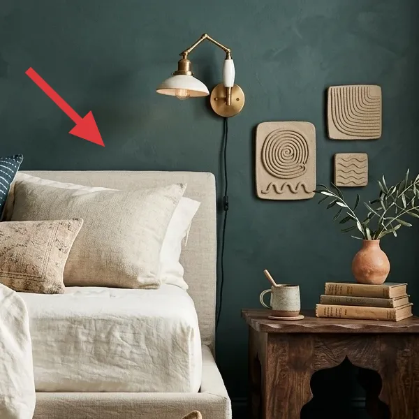 Brass-finished plug-in wall sconce with an adjustable arm and a white metal shade, mounted above the bed.