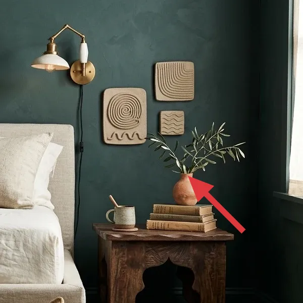 Three textured, natural-toned wall art pieces with organic patterns, mounted on a dark teal wall above a side table.