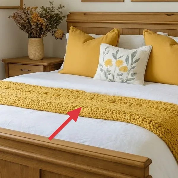 Mustard yellow knit throw draped over the front of the bed