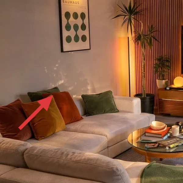 Orange throw pillow on the left sectional with nearby green accent pillow