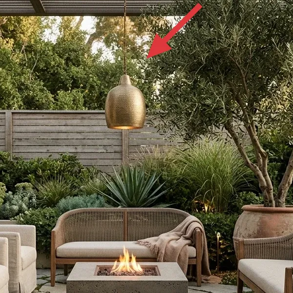 A hammered brass-toned pendant light hanging from a pergola, illuminating the outdoor space.