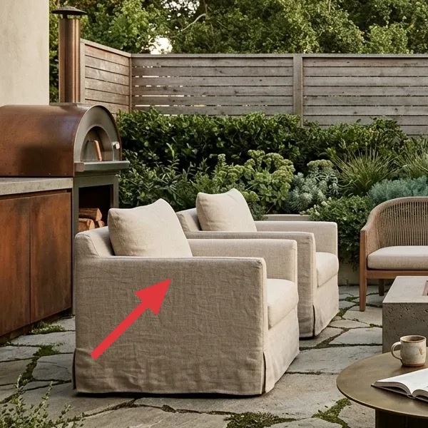 A built-in outdoor pizza oven with a copper finish, next to a concrete countertop and wood storage.